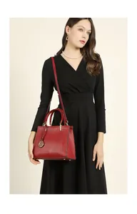 Detail of dark red grain leather tote bag with gold hardware held by a fashion model