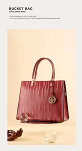 Detail of red leather tote bag with vertical wave texture and golden logo charm accessory
