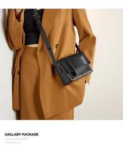Detail of midnight black leather crossbody bag with wide strap on camel suit