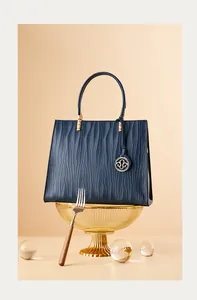 Detail of dark blue leather handbag with wave texture and gold metal hardware