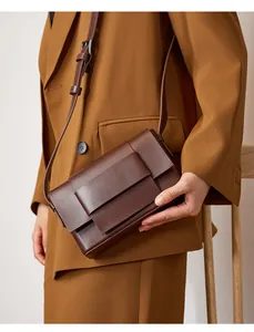 Deep brown leather crossbody bag with adjustable strap worn over minimalist outfit
