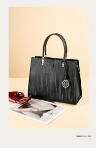Detail of matte black leather handbag featuring 3D wave texture and gold metal accents