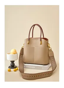 Dettaglio borsa a secchiello in pelle martellata con manico bordeaux e tracolla jacquard