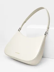 Minimalist cream leather baguette bag with gold lettering and adjustable shoulder strap