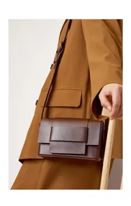 Detail of the minimalist layered flap design on a dark brown leather crossbody bag