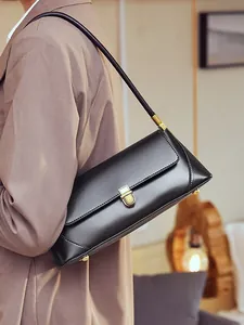 Minimalist black leather baguette shoulder bag with gold hardware for women