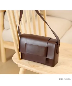 Detail view of deep brown matte leather weave texture on a modern crossbody flap bag