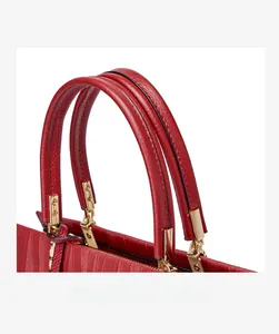 Detailed close-up of the red leather top handle and gold hardware on the handbag