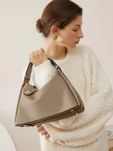 Sac à main triangle en cuir grainé kaki porté avec un pull en tricot blanc élégant