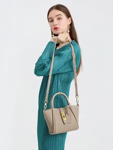 Beige leather bucket bag with top handles and adjustable shoulder strap on a model