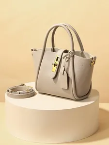 Elegant beige pebbled leather bucket bag with gold buckle on a white pedestal display