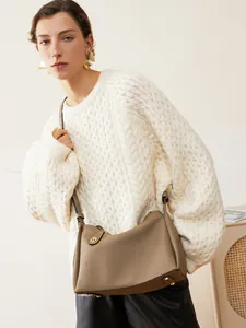 Sac à épaule en cuir grainé marron avec détails dorés porté par un mannequin chic