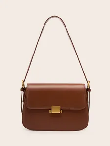 Minimalist caramel brown leather shoulder bag with a square gold buckle on plain background