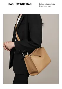 Modella che indossa una borsa a tracolla trapezoidale in pelle marrone con anelli metallici