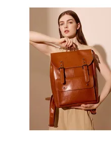 Vintage brown leather backpack detail showing glossy finish and double strap buckle design