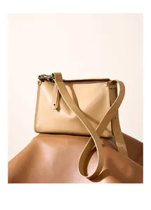 Dettaglio della borsa a tracolla in pelle beige minimalista con fibbia argento e tracolla regolabile