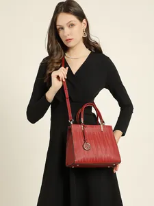 Elegant red leather tote bag with wavy texture and gold charm shown on a model