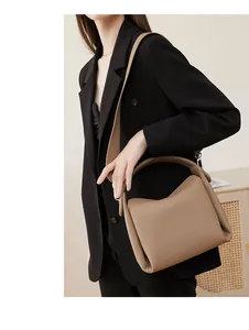 Close-up of beige litchi grain leather shoulder bag showing texture and silver buckles
