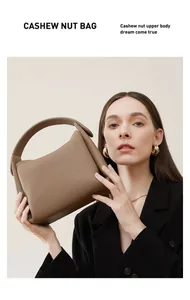 Brown lychee-textured leather cashew nut bag held by a model in a black suit