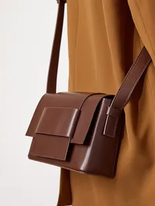 Minimalist deep brown leather crossbody bag featuring a unique double flap boxy design
