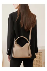 Side view of khaki leather crossbody bag with pleated structure on model in black suit