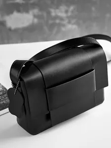 Minimalist black woven leather crossbody bag with dual-layered flap and wide strap