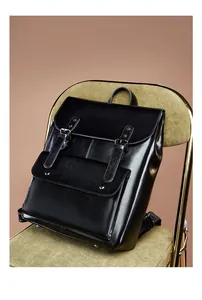 Close-up of vintage black leather backpack with metal buckles on a green corduroy chair