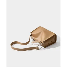 Dettaglio della borsa in pelle color cammello con grande anello d'argento e cuciture rifinite