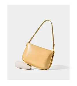 Detail of light yellow leather shoulder bag showing smooth finish and precise stitching