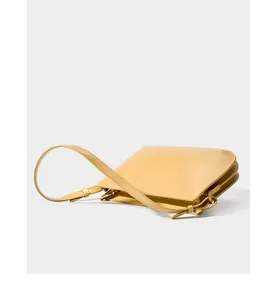 Detail of light yellow leather shoulder bag showing gusseted sides and gold hardware