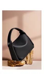 Detail of premium black litchi grain cowhide leather and silver hardware on a crossbody bag