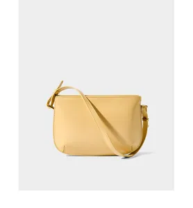 Detail of minimalist bright yellow leather shoulder bag with adjustable strap and stitching