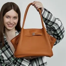Orange-braune Leder-Tragetasche mit eleganter Metallschnalle und doppelten Schultergurten