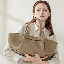 Detail einer großen khakifarbenen Ledertasche mit flügelartiger Faltung und runden Tragegriffen