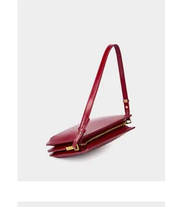 Macro side view of burgundy leather baguette bag with triple-layered gusset detail