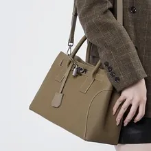 Nahaufnahme der khakifarbenen Ledertasche mit klassischem Verschluss und Metallschloss
