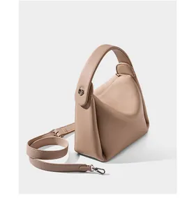 Detailed shot of beige leather shoulder bag with crossbody strap and silver buckles