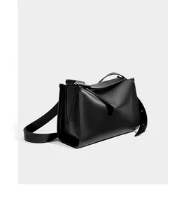Dettaglio della borsa a tracolla in pelle nera minimalista con pieghe geometriche e cuciture