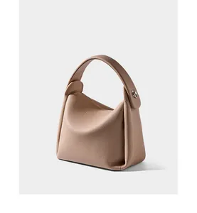 Detail of beige pebbled leather bucket bag featuring structured handle and silver metal hardware