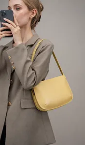 Fashionable yellow leather underarm bag worn by a model in a brown suit for a street look