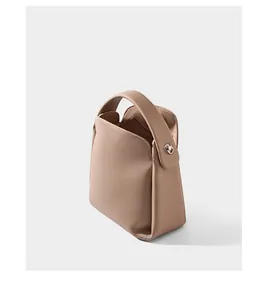Detail of light brown lychee grain leather handbag with silver metal side buckle