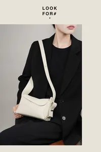 Détail du sac à main en cuir grainé blanc cassé avec bandoulière sur veste noire