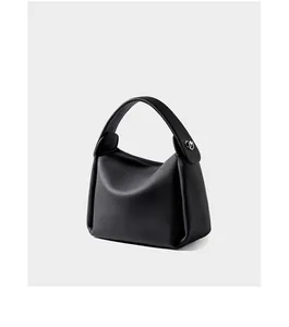 Detail view of black pebble grain leather texture and silver buckle on shoulder bag