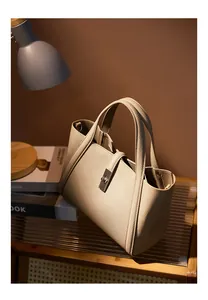 Detail of taupe litchi grain leather tote bag with elegant metal twist lock closure