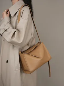 Borsa a tracolla minimalista in pelle marrone con cuciture su trench beige