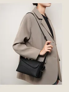 Détail de la bandoulière réglable et boucle en métal doré sur un sac en cuir noir