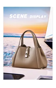 Detailed close-up of textured leather tote bag with silver metal twist lock by the sea