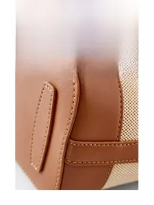 Close-up of the arc-shaped bottom and brown lychee leather stitching on woven bucket bag
