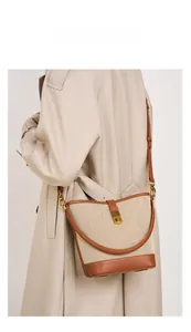 Model shot of canvas bucket bag with brown leather trim and retro gold buckle
