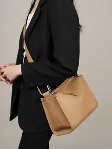 Elegante borsa a spalla in pelle color cammello con anelli argento indossata da modella